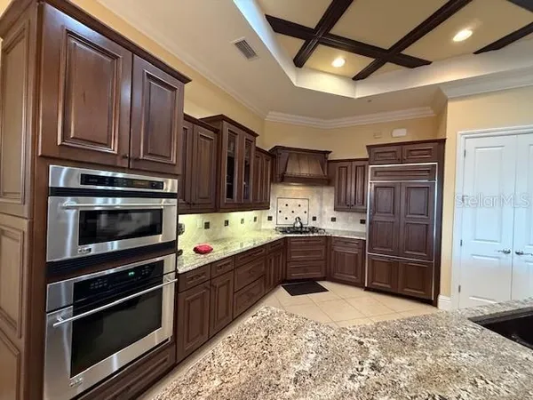a kitchen with stainless steel appliances kitchen island granite countertop a stove refrigerator and cabinets