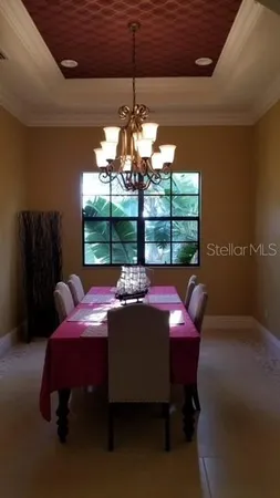 a view of a dining room with furniture a chandelier and window
