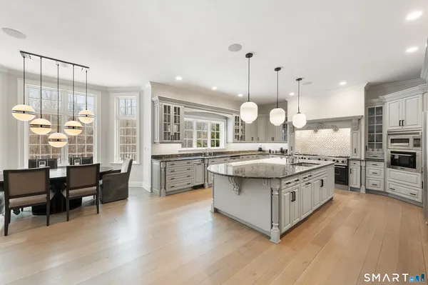 a large kitchen with stainless steel appliances kitchen island granite countertop a large center island and a wooden cabinets