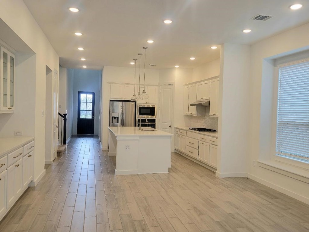 17351 Merigold Hts Drive Conroe, TX 77302 - Photo 11 of 49 a large kitchen with kitchen island a sink a center island stainless steel appliances and a window