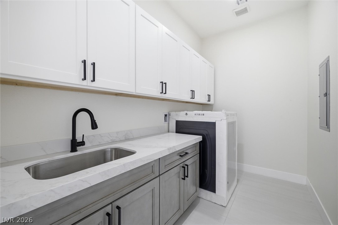 5910 East Kellogg Road Pahrump, NV 89061 - Photo 30 of 58 Functional laundry room equipped with upper and lower cabinetry, a deep basin sink, and a washer.