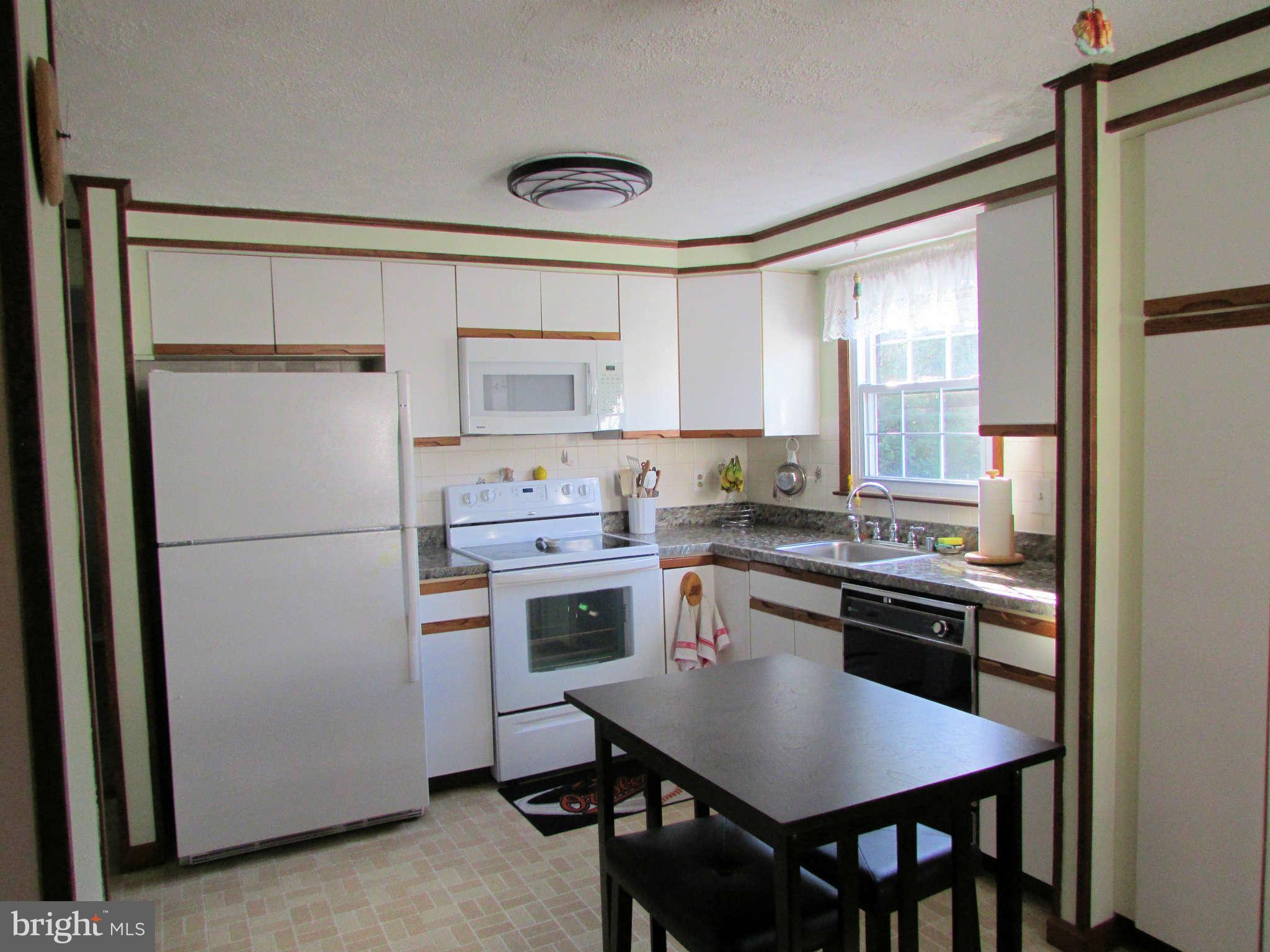 6915 Pinecrest Road Baltimore, MD 21228 - Photo 8 of 30 a kitchen with a refrigerator a stove a sink and a dining table
