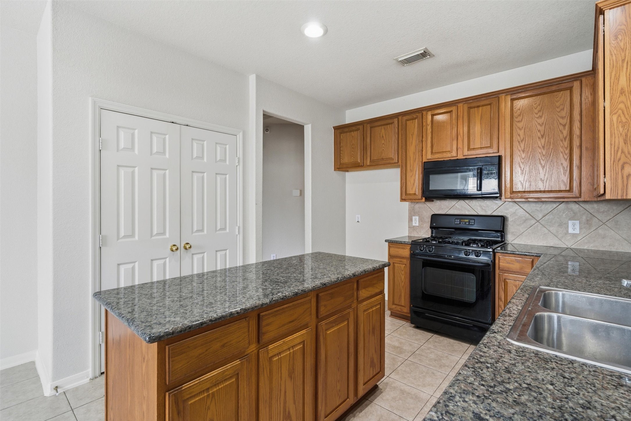 4607 Sebastopol Drive Pearland, TX 77584 - Photo 11 of 26 a kitchen with granite countertop wooden cabinets and a stove top oven