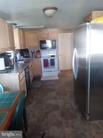 a kitchen with kitchen island granite countertop a refrigerator stove top oven and sink