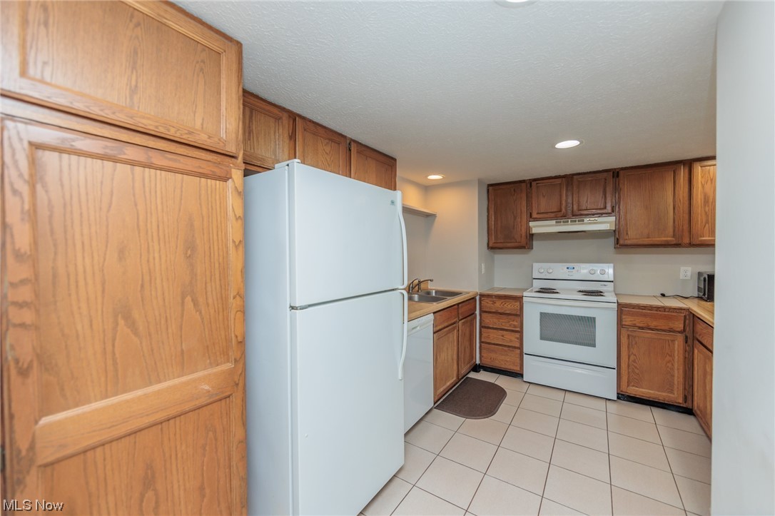 2406 Call Road Stow, OH 44224 - Photo 9 of 30 Kitchen with sink, light tile flooring, white appliances, and a textured ceiling