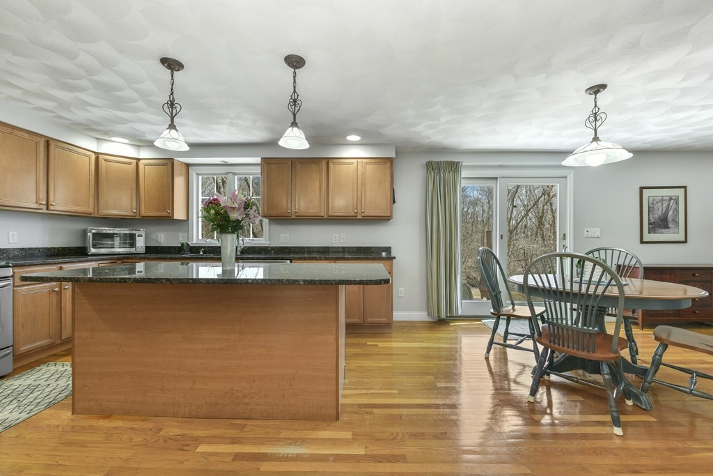 211 Pearl Street Reading, MA 01867 - Photo 9 of 34 a kitchen with stainless steel appliances granite countertop a stove top oven a sink dishwasher a dining table and chairs with wooden floor