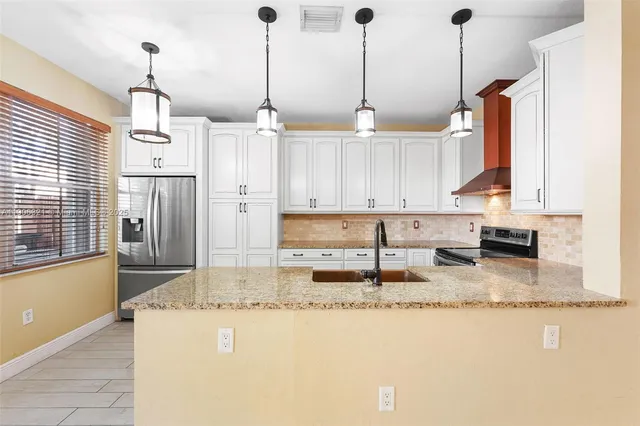 a kitchen with stainless steel appliances granite countertop a sink a stove and a refrigerator