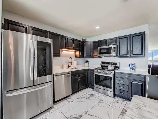 a kitchen with stainless steel appliances granite countertop a refrigerator stove top oven and sink