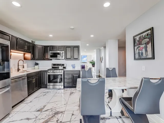 a living room with stainless steel appliances kitchen island granite countertop a sink and cabinets