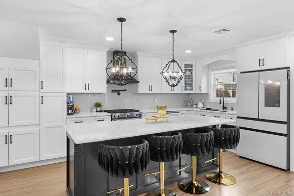 a kitchen with stainless steel appliances granite countertop a sink a stove a refrigerator and chairs