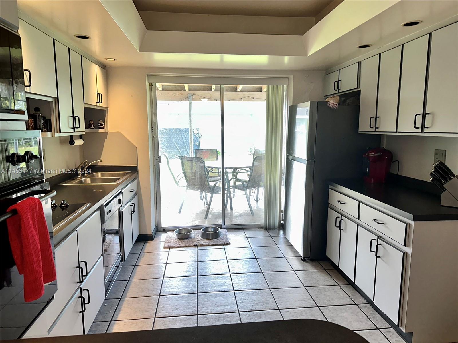 9320 Southwest 125th Terrace Miami, FL 33176 - Photo 5 of 31 a kitchen with stainless steel appliances granite countertop a refrigerator a sink dishwasher and white cabinets next to a window