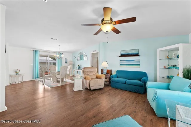 a living room with furniture kitchen view and a chandelier
