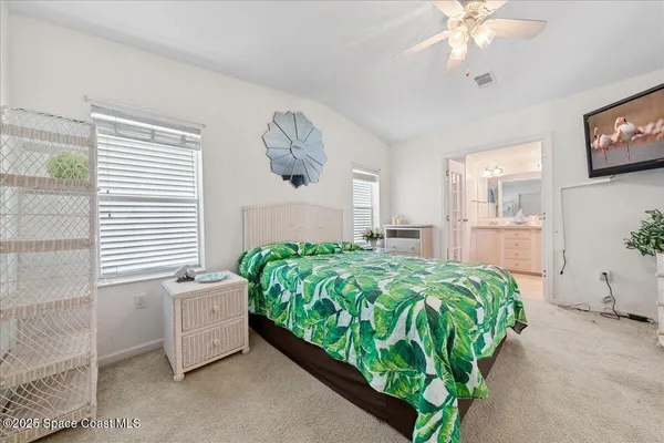 a bed sitting in a spacious bedroom next to a window and a chandelier