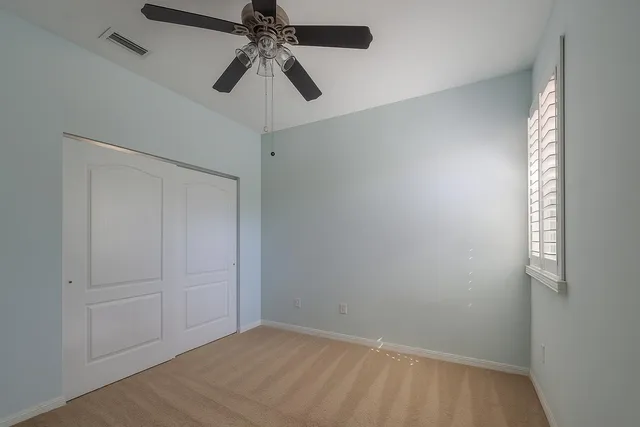 an empty room with a window and a fan