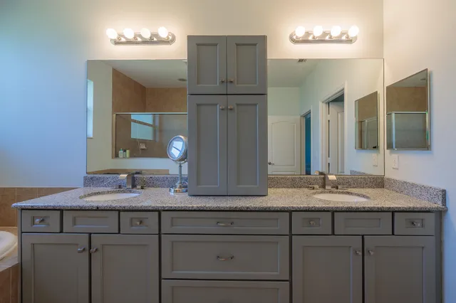 a bathroom with a granite countertop double vanity sink and a mirror