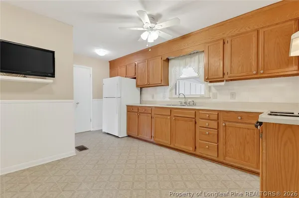 a kitchen with stainless steel appliances granite countertop a refrigerator a sink dishwasher and white cabinets with wooden floor