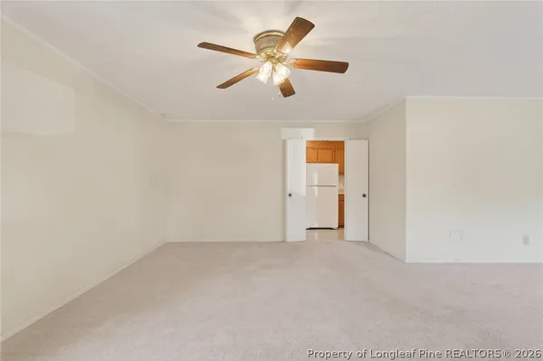 an empty room with chandelier fan and windows