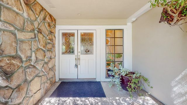 a view of a house with wooden floor and a yard with plants and large trees