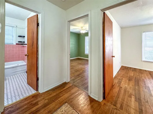 a view of a hallway with wooden floor and bathroom