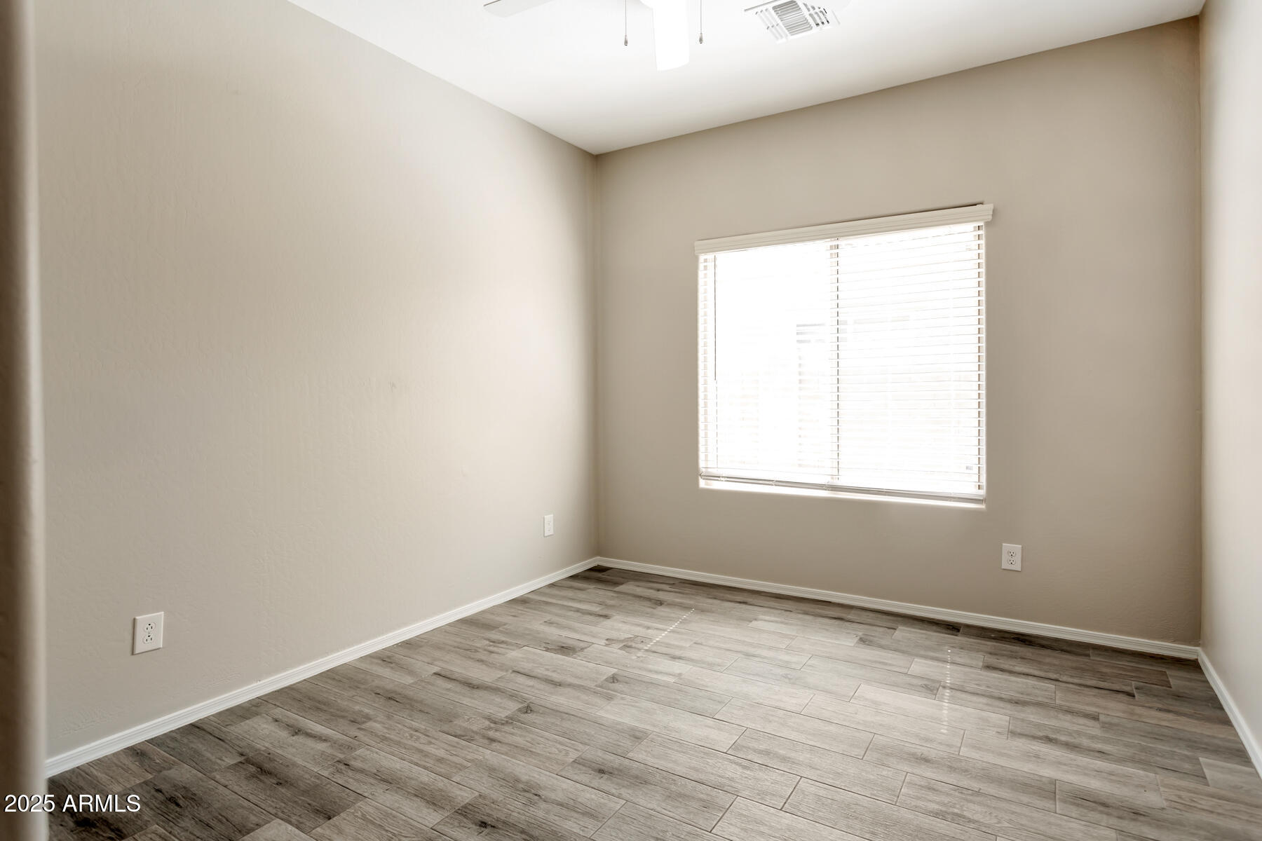 18021 West Tasha Drive Surprise, AZ 85388 - Photo 12 of 16 an empty room with wooden floor and windows