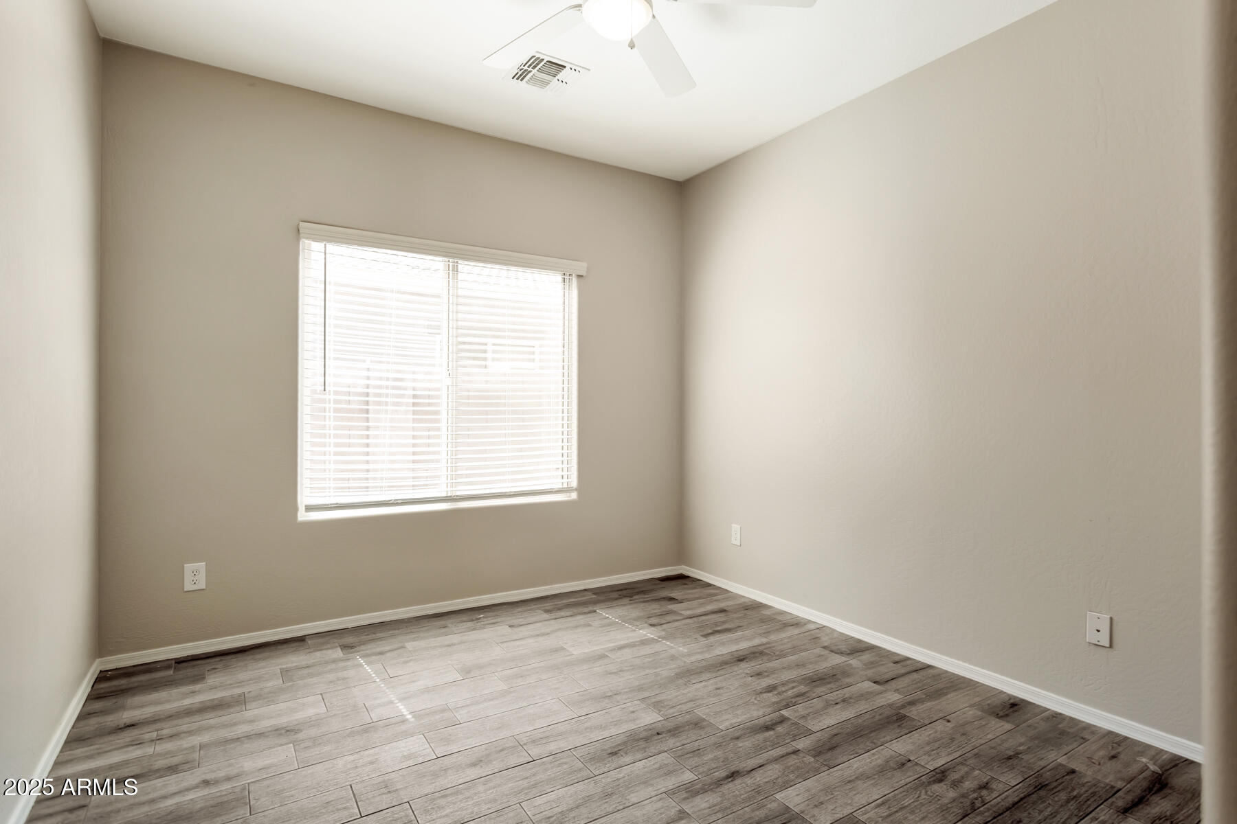 18021 West Tasha Drive Surprise, AZ 85388 - Photo 13 of 16 an empty room with wooden floor and windows