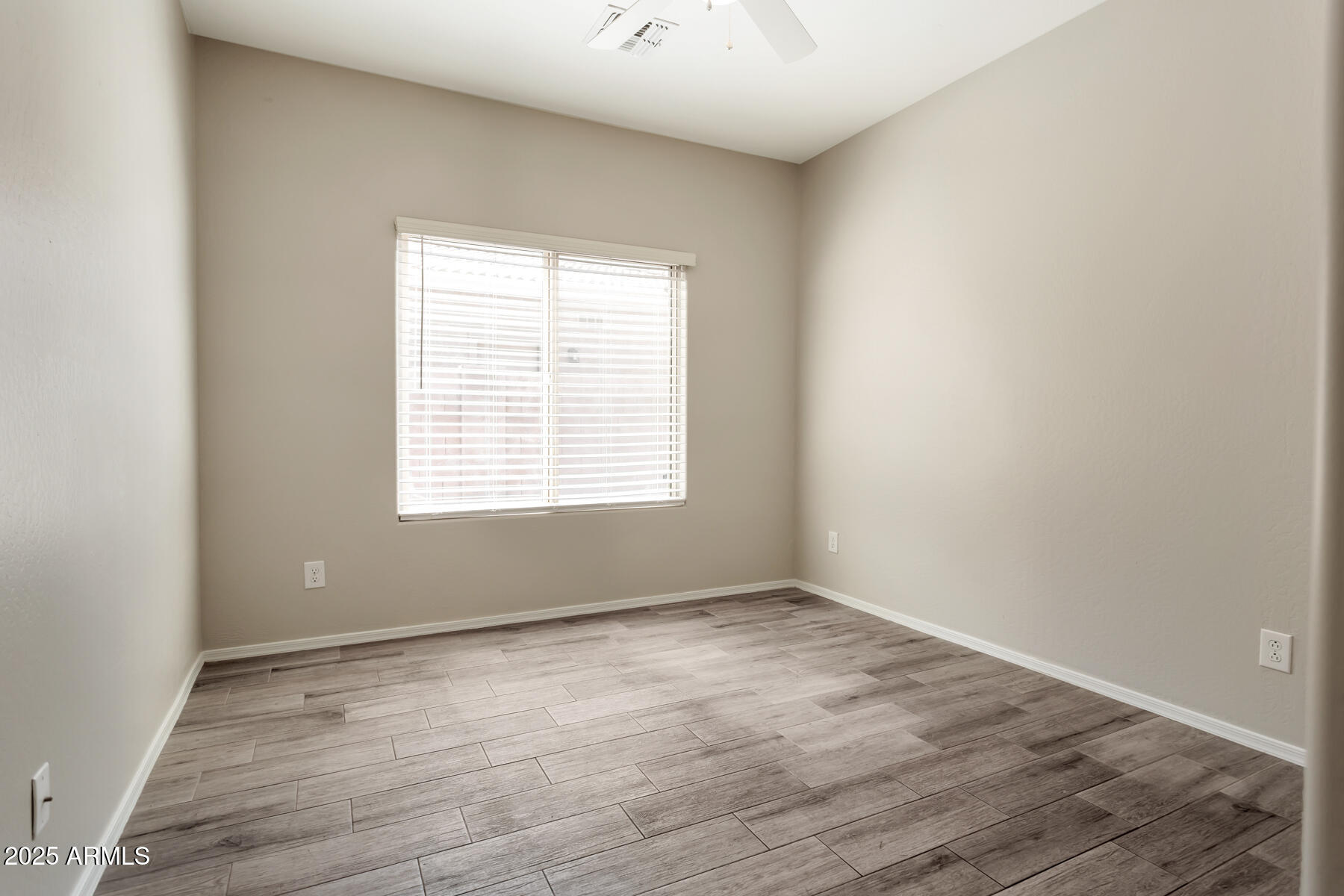 18021 West Tasha Drive Surprise, AZ 85388 - Photo 15 of 16 a view of an empty room with wooden floor and a window