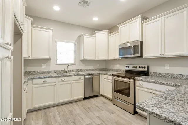 a kitchen with stainless steel appliances granite countertop a stove a sink and a microwave