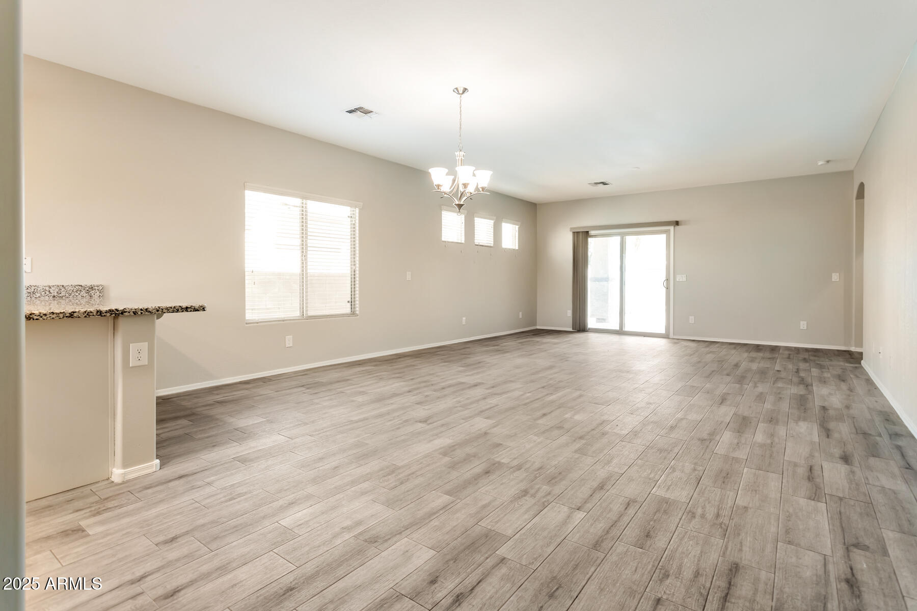 18021 West Tasha Drive Surprise, AZ 85388 - Photo 9 of 16 an empty room with wooden floor and windows