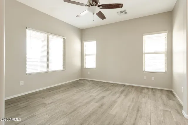 a view of an empty room with a window and a ceiling fan