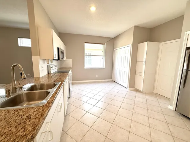 a large white kitchen with a sink a microwave and cabinets