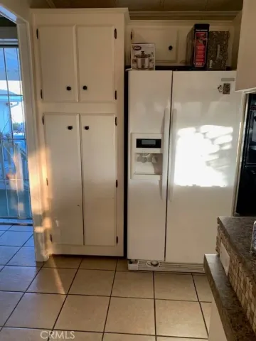 a view of a refrigerator in kitchen and an empty room