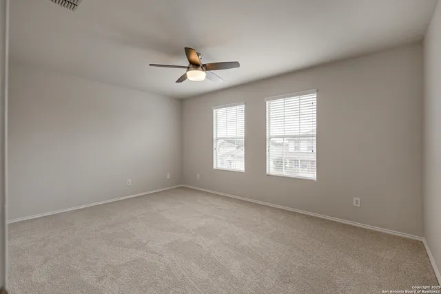 an empty room with a window and a ceiling fan