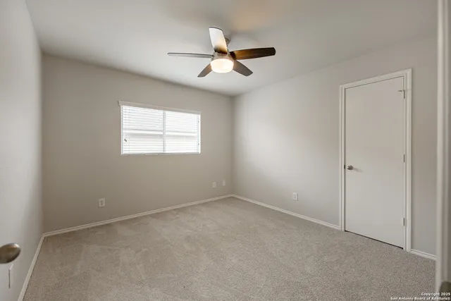 an empty room with window and ceiling fan