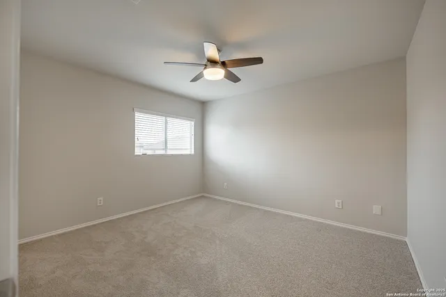 an empty room with a window and a fan