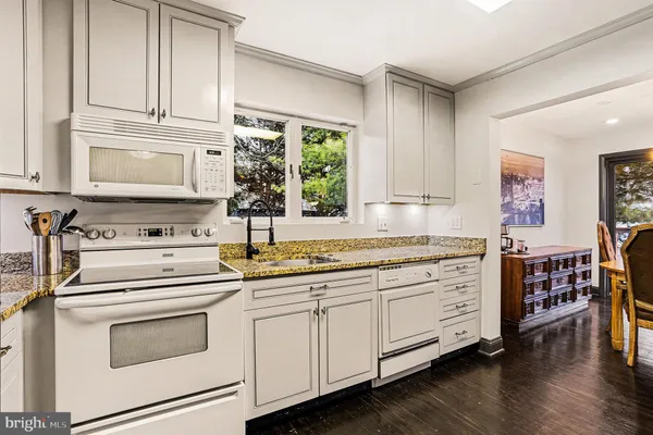 a kitchen with granite countertop white cabinets and white appliances
