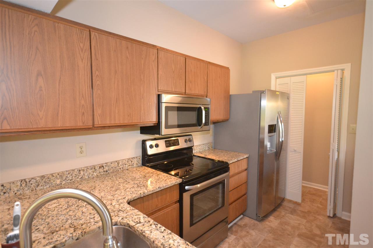 6151 Summer Pointe Place, Unit 103 Raleigh, NC 27606 - Photo 6 of 12 Kitchen features stainless steel appliances and closet space for laundry. Washer, dryer, and refrigerator to convey.