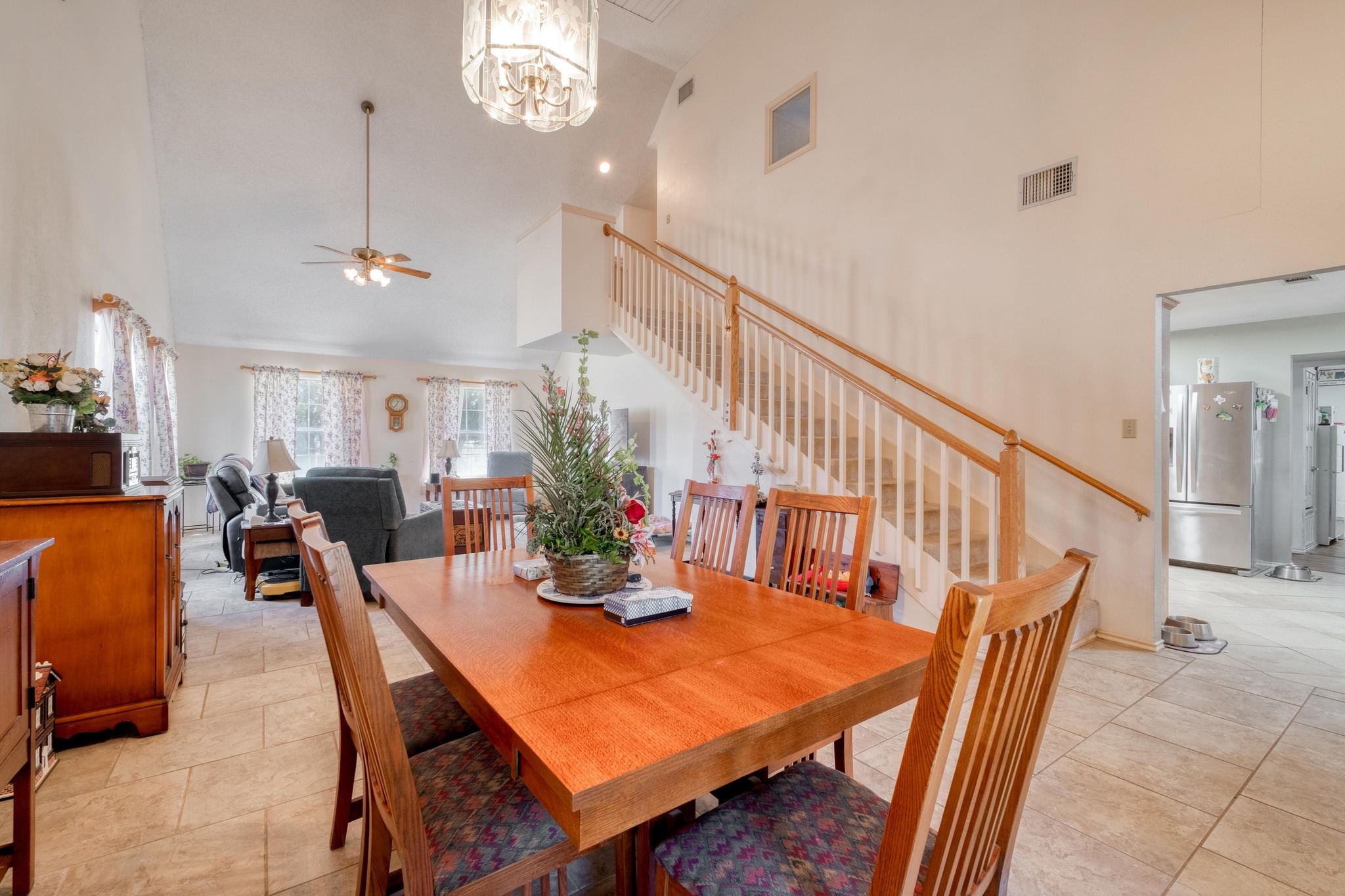 153 Pleasant Grove Road Elgin, TX 78621 - Photo 12 of 34 Dining space featuring high vaulted ceiling, stairs, ceiling fan, a chandelier, and light tile patterned floors