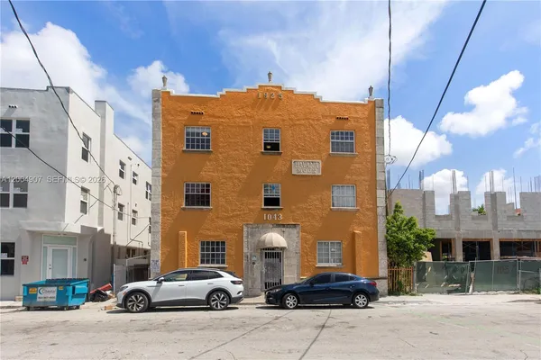 a front view of a building with cars parked