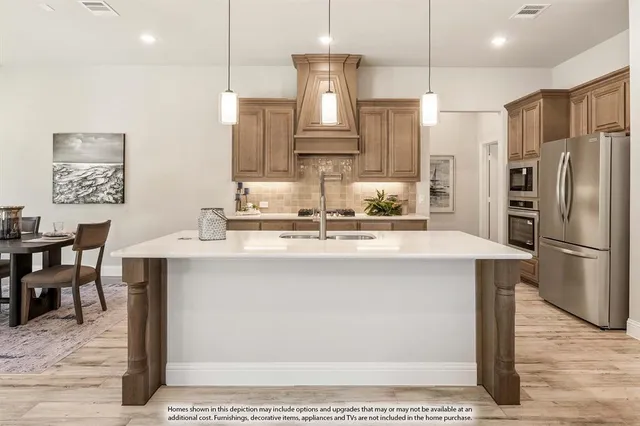 a kitchen with stainless steel appliances a refrigerator a sink a stove a dining table and chairs