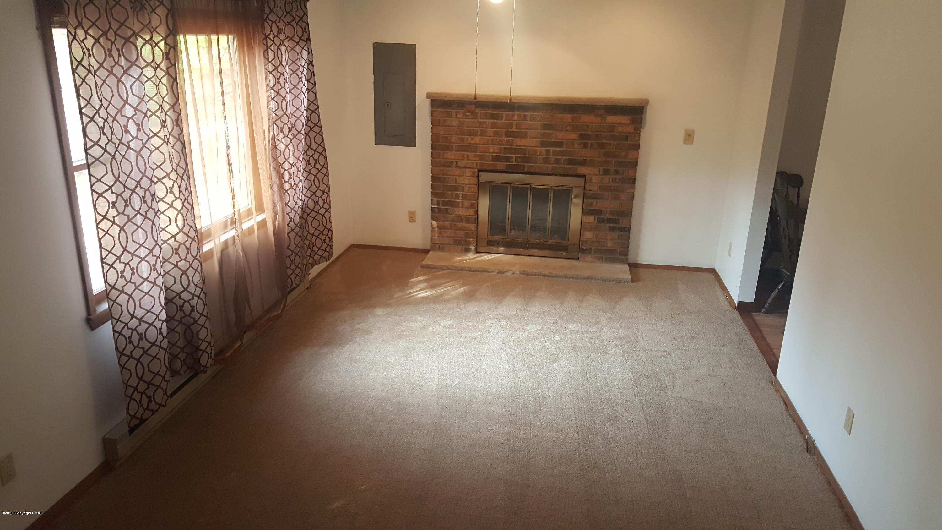 114 Weasel Road Dingmans Ferry, PA 18328 - Photo 4 of 51 an empty room with wooden floor fireplace and windows