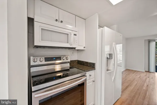 a kitchen with granite countertop cabinets stainless steel appliances and wooden floor
