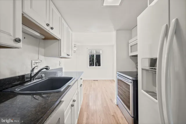 a kitchen with a sink a refrigerator and cabinets
