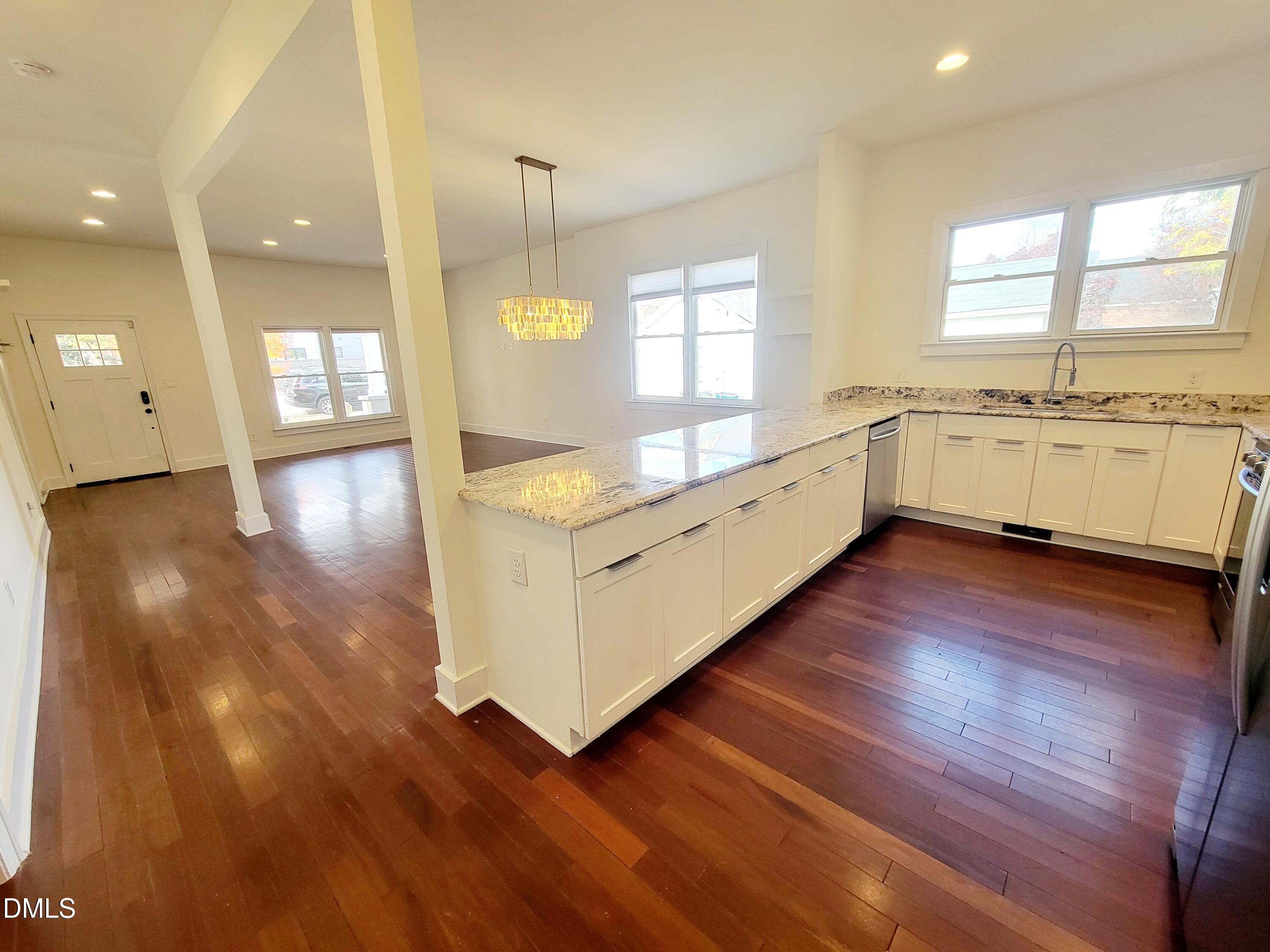 707 South East Street Raleigh, NC 27601 - Photo 11 of 46 a large white kitchen with granite countertop a stove top oven a sink and white cabinets with wooden floor