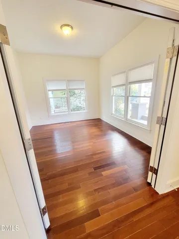a view of an empty room with wooden floor and a window