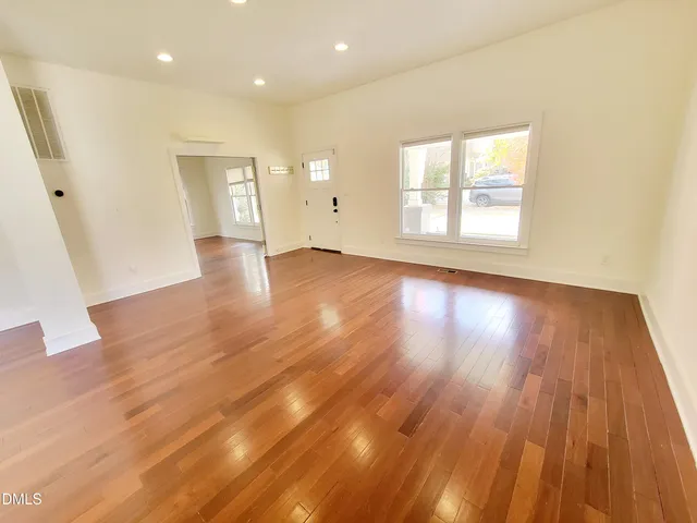 a view of an empty room with wooden floor and a window