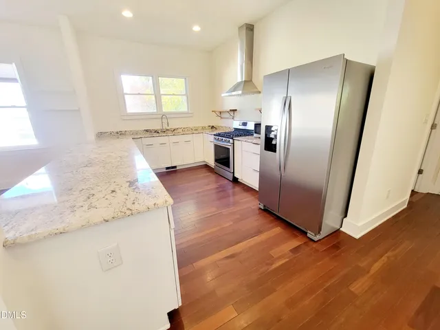 a kitchen with granite countertop white cabinets and stainless steel appliances