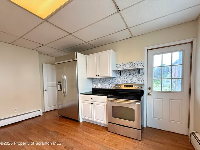 a kitchen with granite countertop a stove a sink dishwasher and a refrigerator with wooden floor