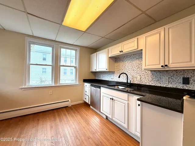 a kitchen with granite countertop wooden floors and white cabinets