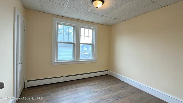 an empty room with wooden floor and windows