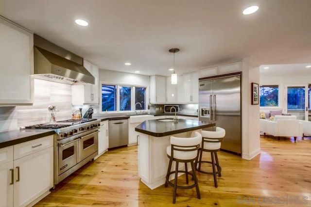 a kitchen with stainless steel appliances granite countertop a sink a stove and a refrigerator